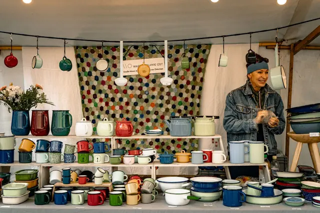 A vendor selling handmade pottery at an outdoor market